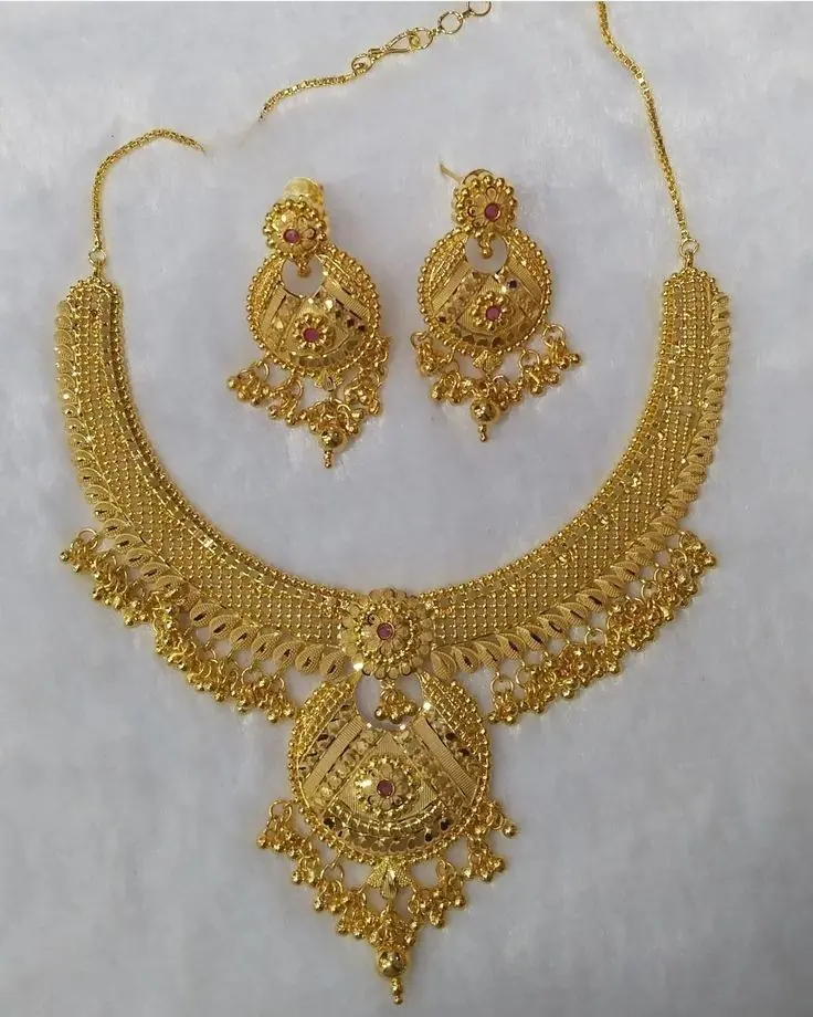 Gold necklace and jhumka earring set on white fabric
